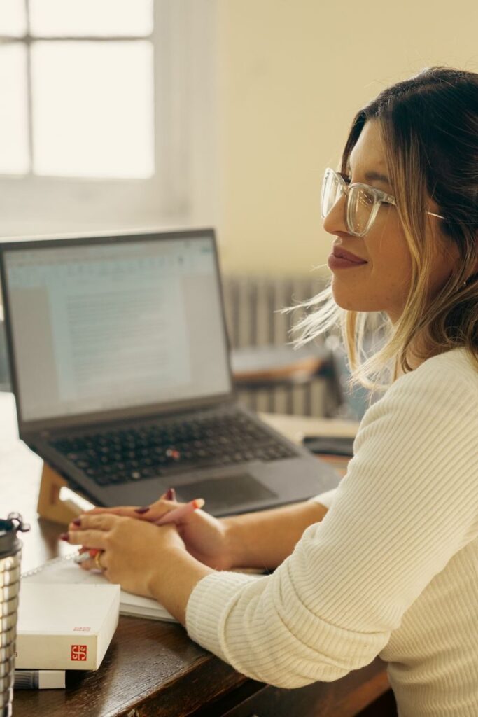 A woman working attentively at a desk with a laptop, creating a study environment.