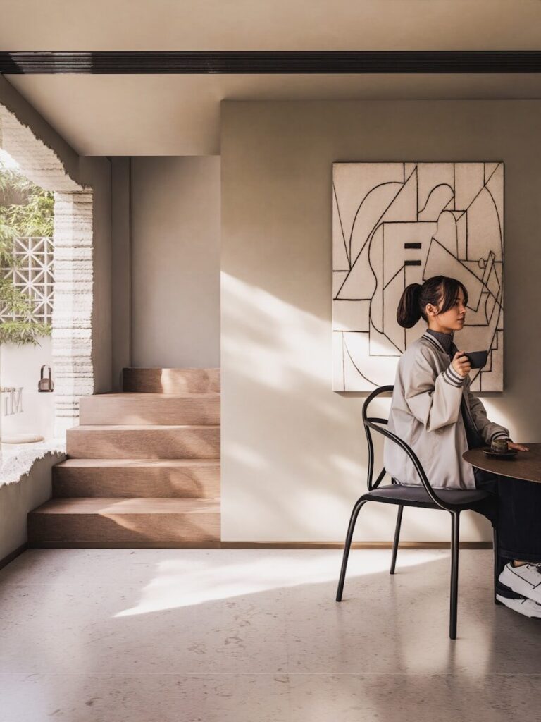 Woman sips tea in a minimalist, modern cafe.