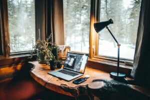 Laptop open on a minimal wood desk near a window
