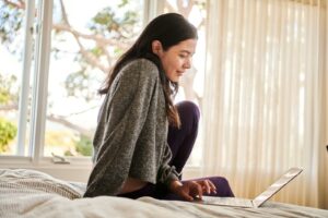 A woman on a bed working on laptop to move therapy website from Wix to WordPress